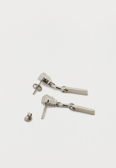 Ασημί σκουλαρίκια με σταγόνα και ορθογώνια κρεμαστά, με κλιπ πεταλούδας, σε απλό λευκό φόντο.