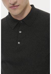 Dunkelgraues Poloshirt mit weicher Textur, klassischem Kragen und einer Drei-Knopf-Leiste mit runden, grauen Knöpfen.
