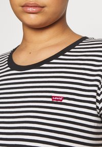 Sort-hvid stribet T-shirt lavet af blødt stof. Har en rund halsudskæring og et lille rødt Levi's-logo på venstre bryst.