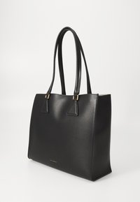 Geantă tote din piele neagră cu textură netedă, design unghiular și două mânere lungi. Dispune de accesorii în nuanță de aur și branding minim pe față.