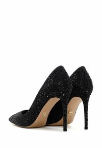 Des talons aiguilles noirs ornés de grappes de perles noires, avec un bout pointu, et une semelle beige lisse avec un logo doré sur le talon.
