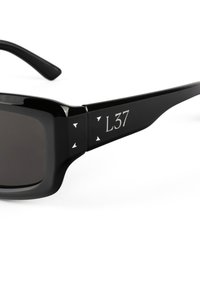 Mustad must have paksed raamiga ja tumedate läätsedega prillid. Omab hõbedaseid aktsente ja kolmnurkseid detaile külgedel. Mudel tähistatud "L37."