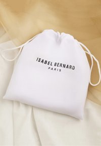 Witte trekkoordzak gemaakt van gladde stof, met zwarte tekst "ISABEL BERNARD PARIS" in een modern lettertype. Geaccentueerd door een lichte achtergrond.