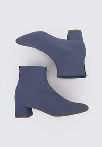 Bottines bleues à chevilles avec un dessus en tissu extensible, bout pointu et un talon épais. Texture lisse avec un design minimaliste.