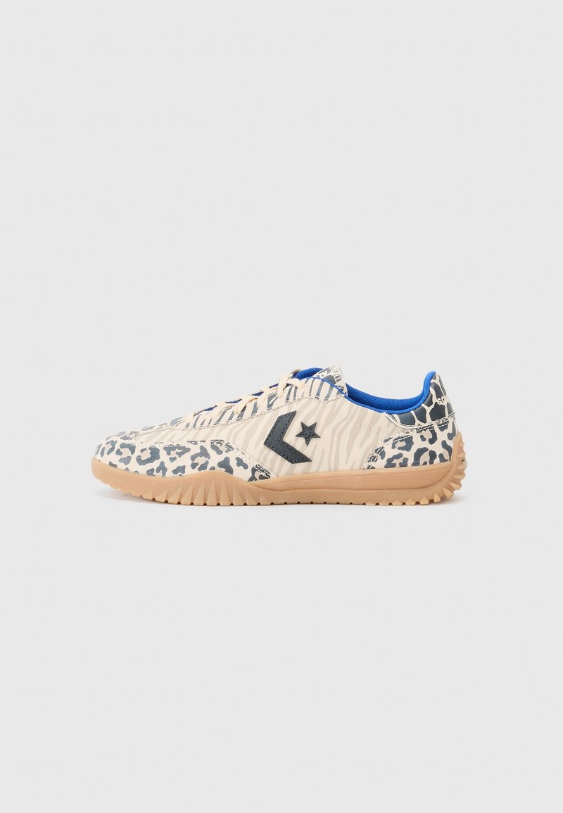 Les baskets présentent une tige beige avec des motifs léopard et zèbre, une doublure bleue et un logo étoile gris foncé ; une semelle extérieure en caoutchouc gomme avec une traction texturée.