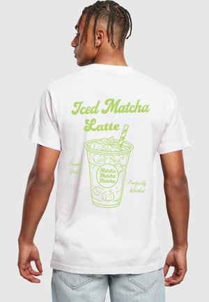 Biała koszulka z zielonym grafiką przedstawiającą kubek z napisem "Iced Matcha Latte" oraz kostkami lodu i liśćmi mięty.