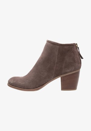 Bottine en daim marron avec un bout arrondi, fermeture éclair à l'arrière et un talon bloc en bois. Texture lisse partout.