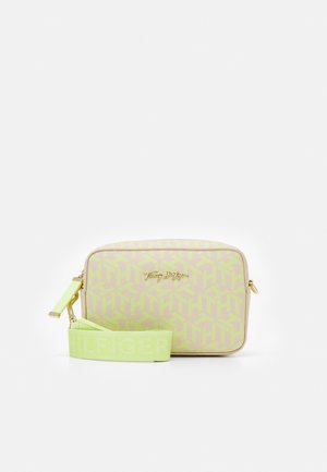 Sac bandoulière rectangulaire beige avec motif géométrique jaune-vert, plaque logo dorée et large sangle jaune-vert avec nom de marque embossé.