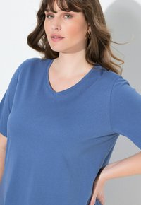 Blå kortärmad T-shirt med V-ringning, tillverkad av mjukt bomullstyg, med en slät yta och avslappnad passform.