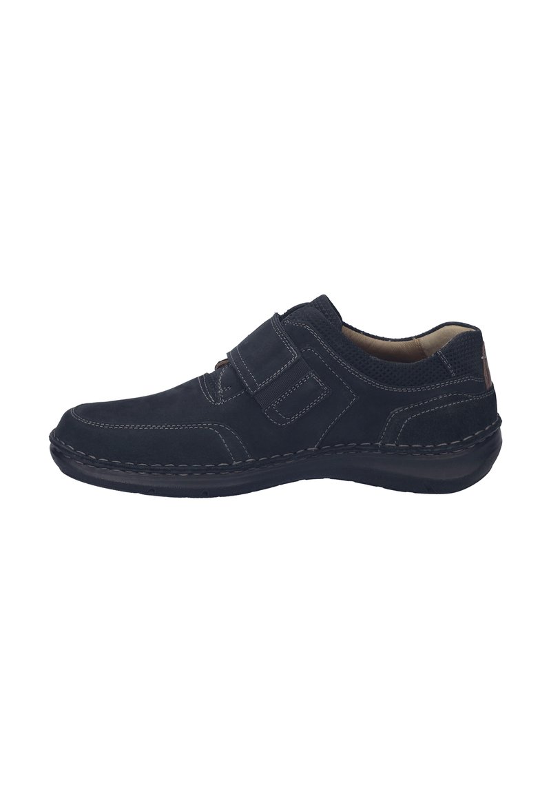 Scarpa in suede nera con punta arrotondata, dettagli cuciti e chiusura a strappo. Suola flessibile e interno imbottito per maggiore comfort.