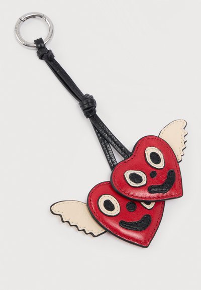 Μπρελόκ με δύο κόκκινες δερμάτινες καρδιές που έχουν ραμμένα χαμογελαστά πρόσωπα και κρεμ φτερά, συνδεδεμένες σε ασημένιο μεταλλικό δαχτυλίδι με μαύρα δερμάτινα λουριά.