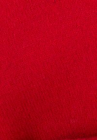 Tessuto lavorato a maglia rosso con una superficie texture, caratterizzato da una trama fitta e fibre visibili, che mette in risalto una tonalità ricca e vibrante.