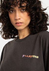 Mustat puuvillapaidat, joissa on monivärinen "BILLABONG"-logo gradienttina. Klassinen pyöreä kaula-aukko ja normaali istuvuus. Pehmeä pinta.