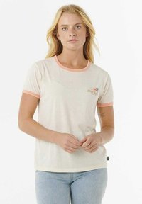 T-shirt de couleur crème avec un col et des manches côtelés roses, comportant une petite impression de palmiers et de soleil sur la poitrine gauche.