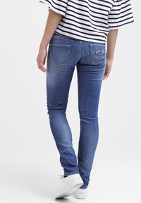 Smala blå denimjeans med en urtvättad finish, som har två bakfickor och broderade detaljer. Bärs med en randig topp och vita sneakers.