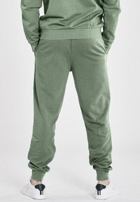 Välanpassade gröna joggers gjorda av mjukt tyg, med elastisk midja och avslutade vristerna. Bärs med vita sneakers med klackdetaljer.