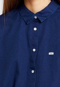 Marineblauw overhem shirt gemaakt van zachte stof, met een klassieke kraag, witte knopen en een klein Lee-logo label aan de linkerkant.
