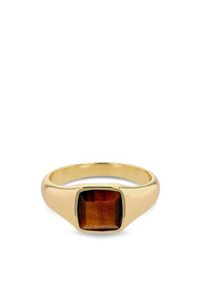 Anillo de oro con una piedra preciosa ojo de tigre marrón de forma cuadrada en el centro sobre un fondo blanco.