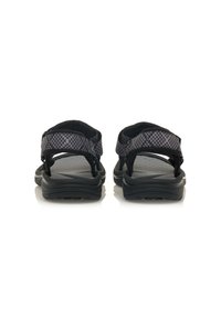 Sandalias negras con una parte superior de tela texturizada, dos correas ajustables y una suela acolchada. La vista trasera resalta el diseño minimalista y el agarre.