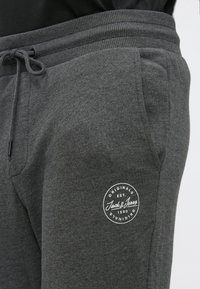 Donkergrijze sweatpants met een voorzak, geribde tailleband, trekkoord en een wit rond Jack & Jones logo op de dij.