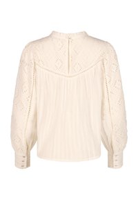 Blouse blanc crème avec manches longues bouffantes, détails en dentelle à œillets sur le haut du dos et les manches, et poignets boutonnés.