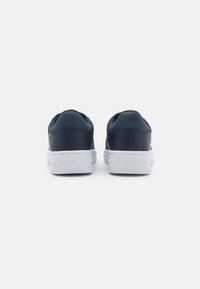 Sneakers in pelle blu con una superficie liscia, suole in gomma bianca e design minimalista, dotati di supporto imbottito alla caviglia e dettagli di cucitura.
