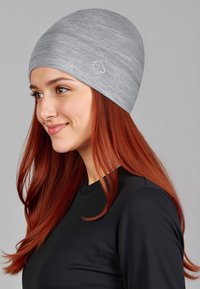 Grijze gebreide muts met een nauwsluitende pasvorm, met een gladde textuur en subtiel gemêleerd patroon. Klein logo-accent aan de zijkant.