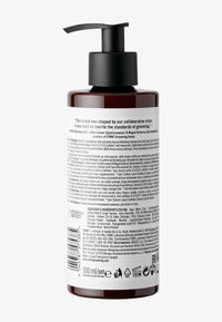Bärnstenfärgad flaska med en svart pump, som rymmer 300 ml. Vit etikett med flerspråkig text, ingredienser och bruksanvisning på baksidan.
