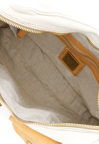 Interno della borsa di tela con rivestimento beige, dettagli in pelle gialla, una tasca con zip e un'etichetta metallica con il nome.
