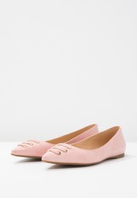 Ballerine in suede rosa con punta affilata, dotate di una fascia decorativa con hardware dorato sul davanti. Suola piatta.