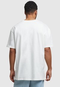 Hvid bomulds t-shirt med korte ærmer og en afslappet pasform, med en rund halsudskæring, synlige stikninger og en glat tekstur.