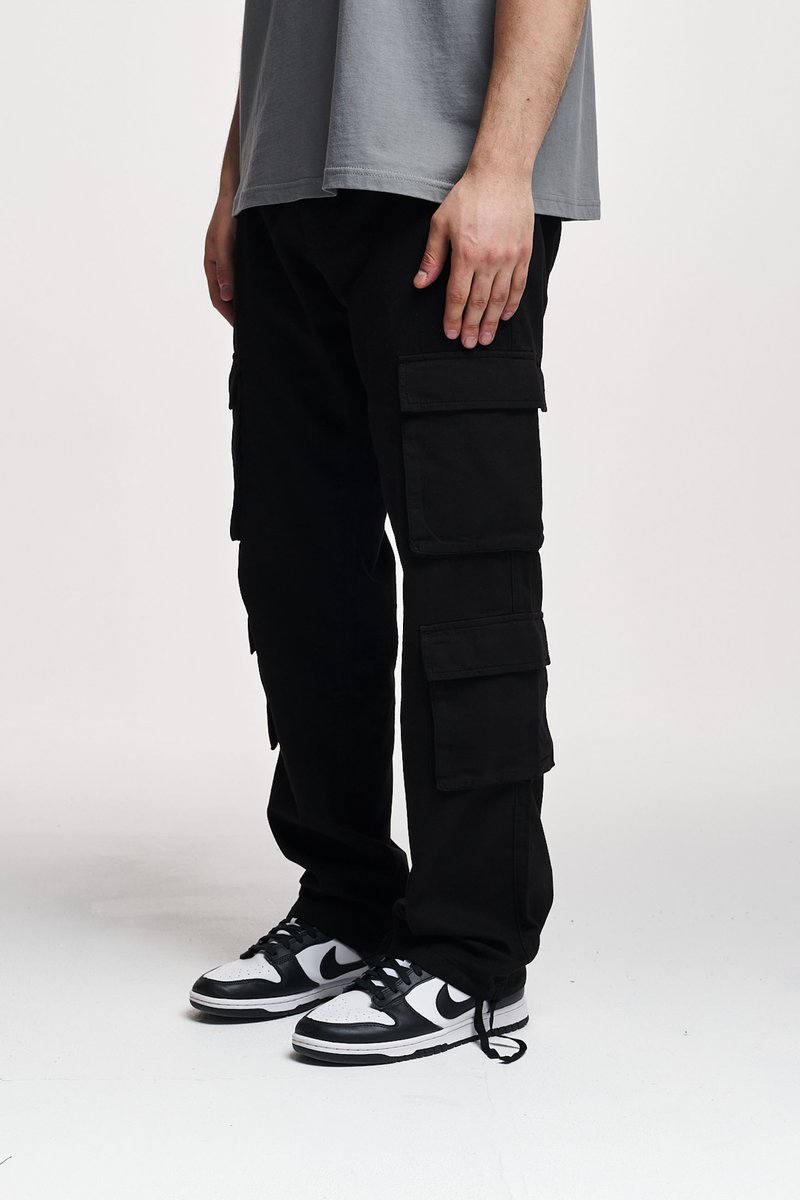 Pantaloni cargo negri cu multiple buzunare laterale, croi lejer, dintr-un material durabil. Asortați cu adidași negri și albi cu șireturi.