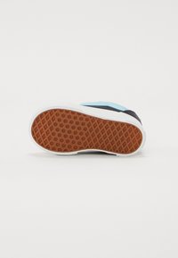 Schuh mit einem dunkelblauen und hellblauen Obermaterial, weißer Sohle und einer strukturierten braunen Gummisohle, die ein Rautenmuster für besseren Halt aufweist.