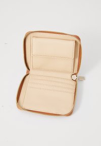 Portefeuille zippé en cuir beige clair avec des accessoires dorés. Il présente une fente pour cartes intérieure et une texture lisse, avec une garniture orange contrastante.