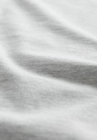Valge puuvillane kangas, millel on sile tekstuur, minuti voldid ja kortsud, näidates paindlikkust ja pehmust.