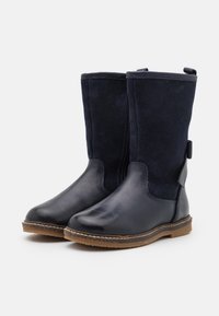 Botas azul marino oscuro con parte inferior de cuero y parte superior de ante suave, con acabado texturizado y suela marrón resistente.