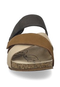 Strappy sandal featuring overlapping leather bands in black, brown, and beige, with a textured beige footbed and a cork-like sole.