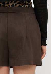 Brune semskede shorts med en glat overflade og skræddersyet pasform, der har en skjult lynlås i taljen og en ren søm.
