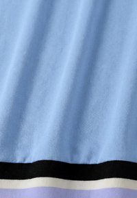 Tissu bleu clair doux avec une texture lisse au-dessus de rayures horizontales en noir, blanc et lavande sur le bord inférieur.