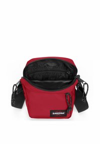 Röd Eastpak-väska med en enkel design, som har dragkedjestängning, svart inredning och justerbar rem. Hållbart tyg och märkesskylt.