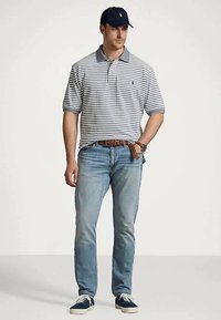 Herrens poloskjorte med grå og marineblå striper, kombinert med lyseblå jeans. Tilbehør inkluderer en marineblå caps og hvite joggesko. Enkel design.