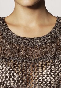 Strickoberteil mit rundem Ausschnitt, das eine lockere, offene Maschenstruktur in dunkelbrown und beige Tönen zeigt und ein strukturiertes Muster hervorhebt.