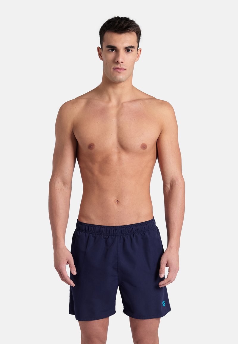 Costumi da bagno blu navy con elastico in vita, caratterizzati da un piccolo logo turchese. Realizzati in tessuto leggero, con taglio fino al ginocchio.