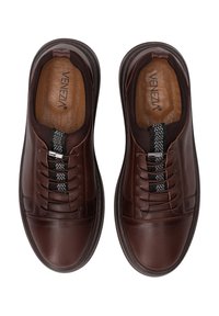 Brązowe skórzane sneakersy o gładkiej powierzchni, czarne elastyczne sznurówki i wzorzysta paskowa aplikacja. Wyściółka z miękkim wypełnieniem i niski profil podeszwy.