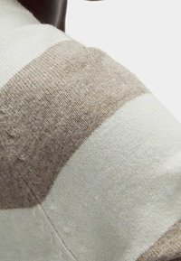 Lekki sweter z szerokimi paskami w kolorze beżowym i off-white, o miękkiej teksturze i widocznym wzorze dzianiny. Akcenty delikatnego puszystości.