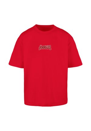 Červené bavlněné tričko s uvolněným střihem. Má výrazné grafické logo v kontrastní barvě na přední straně. Krátké rukávy a kulatý výstřih.