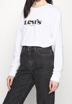 Vit långärmad t-shirt med svart "Levi's"-logotyp, tillsammans med högmidjade mörk denimjeans med en klassisk femfickdesign.