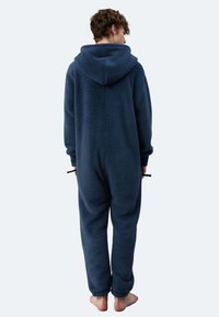 Dunkelblauer Fleece-Einteiler mit Kapuze, der eine strukturierte Oberfläche und eine lockere Passform aufweist. Keine sichtbaren Verschlüsse und barfuß.