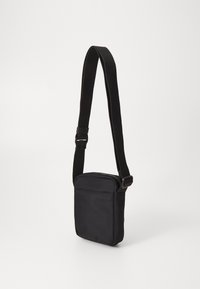 Borsa a tracolla nera in tessuto con strap regolabile, forma rettangolare, esterno testurizzato e tasca frontale con zip per riporre oggetti.