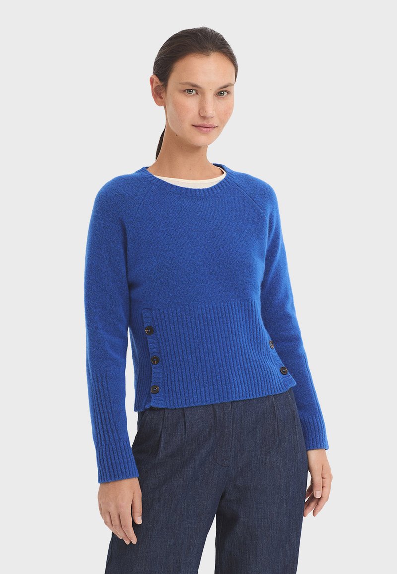 Blue ribbed sweater with a crew neck and long sleeves, featuring a textured body and button accents on the left side.